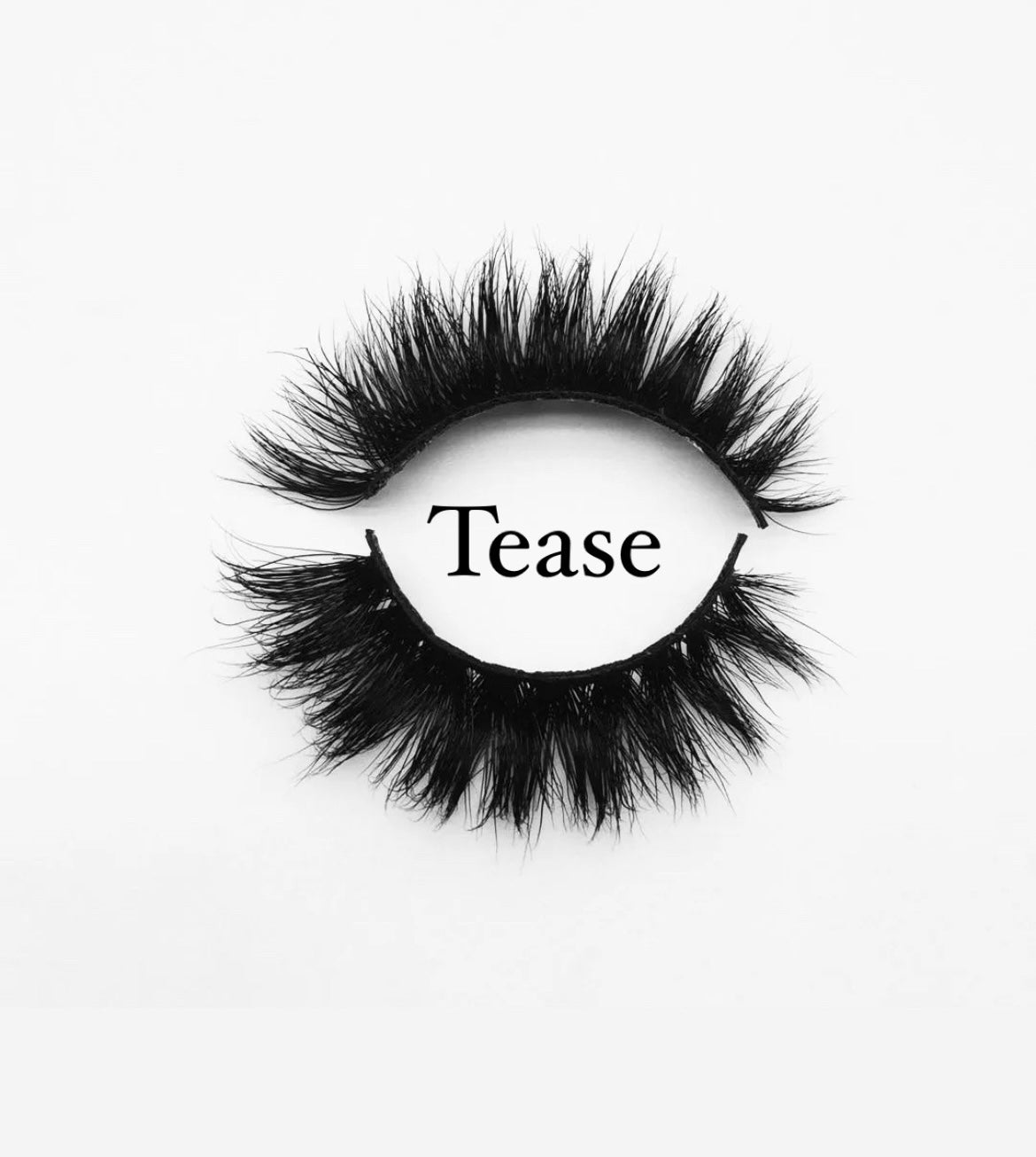 A pair of fluffy, black MesmerEyes Mink Lashes by Nayy Seduction Brand is displayed in the shape of an eye on a white background. The word "Tease" is written in the center of the eyelashes.